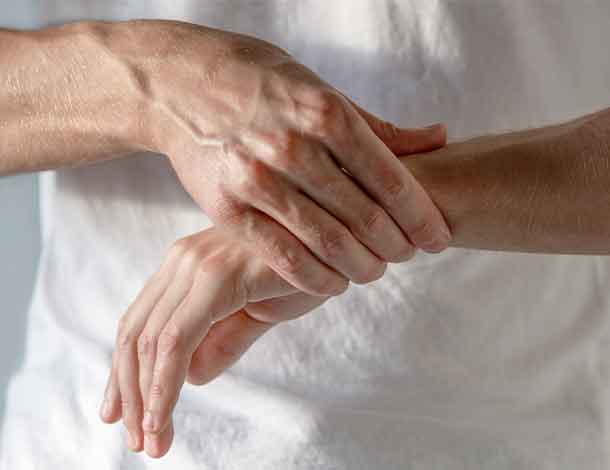 man with wrist arthritis holds his hand
