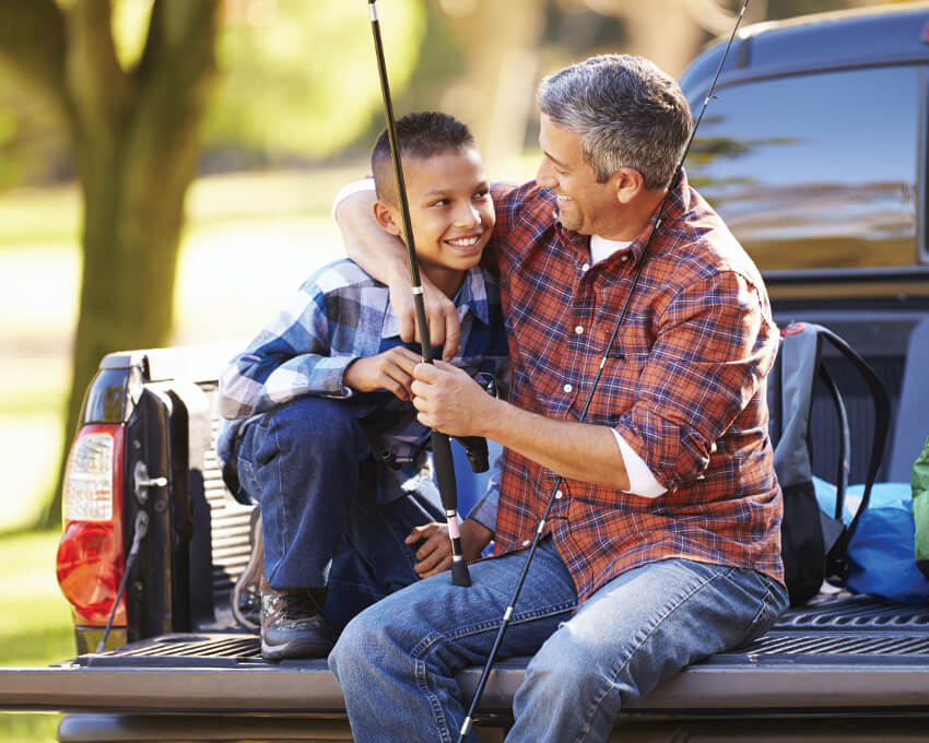 Father and son sitting on truck tailgate